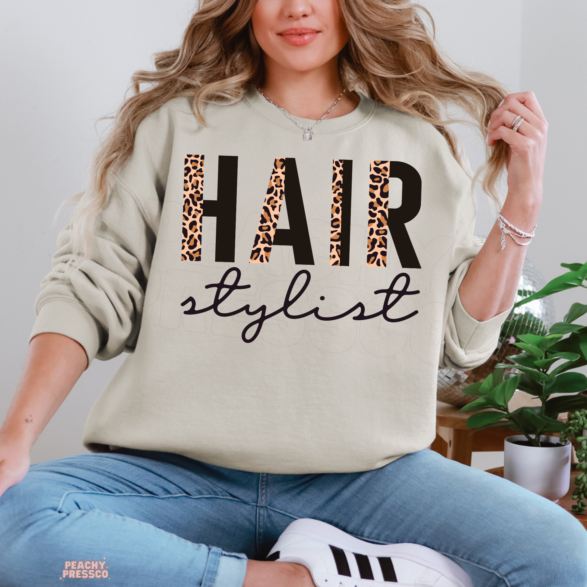 Sand-colored crewneck sweatshirt with a leopard print Hair Stylist graphic, perfect for salon owners, hairstylists, cosmetologists, and beauty industry professionals.