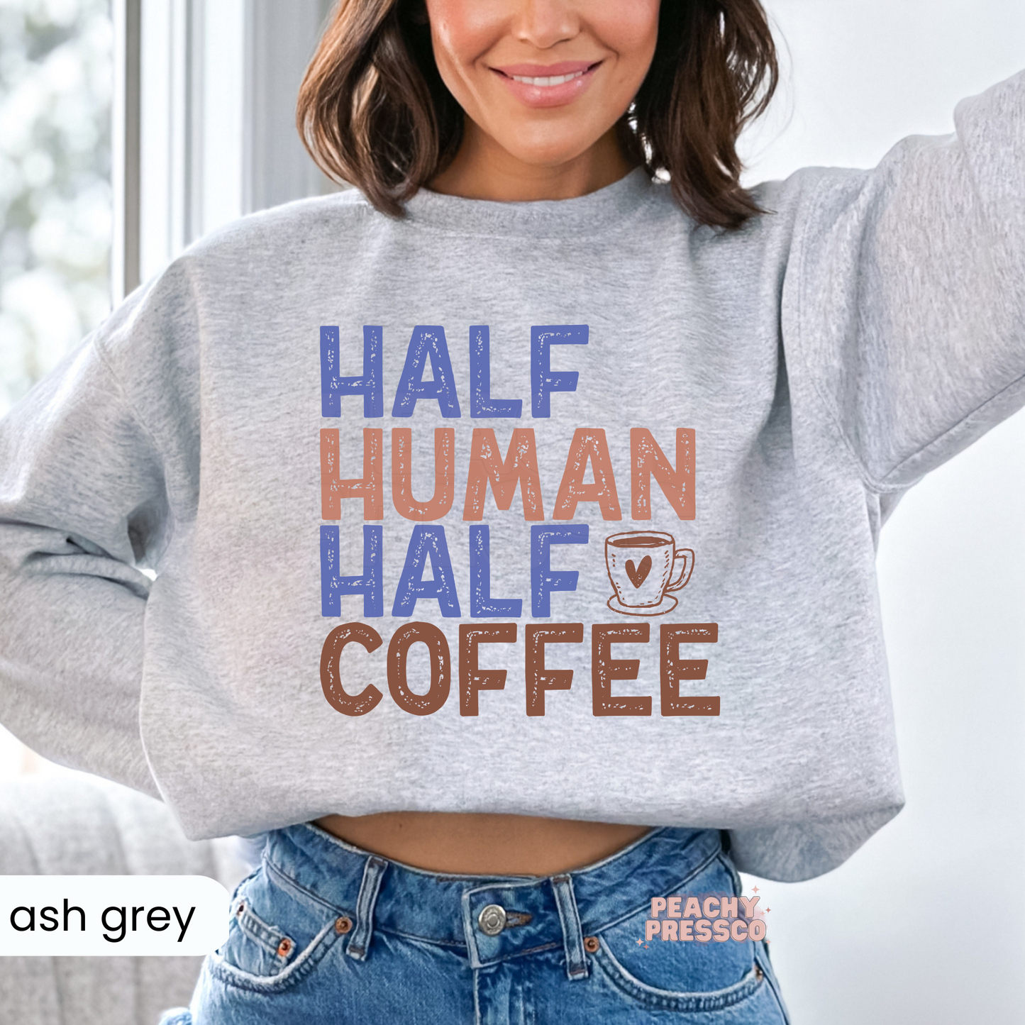 Ash grey crewneck sweatshirt featuring the funny "Half Human Half Coffee" graphic in distressed retro lettering with a coffee cup design.