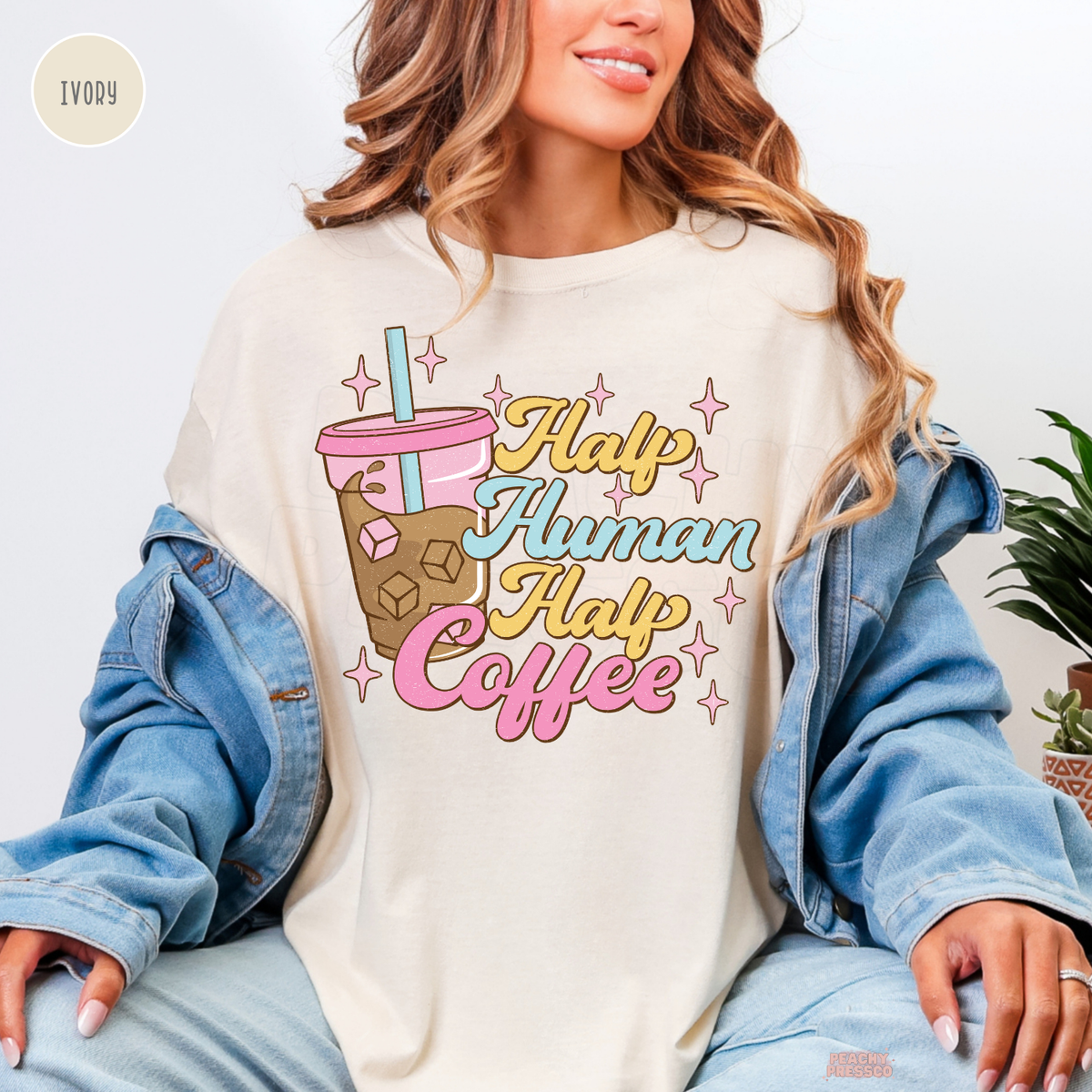 Half Human Half Coffee ivory shirt featuring a retro iced coffee cup, pink sparkles and colourful yellow, blue and pink lettering.