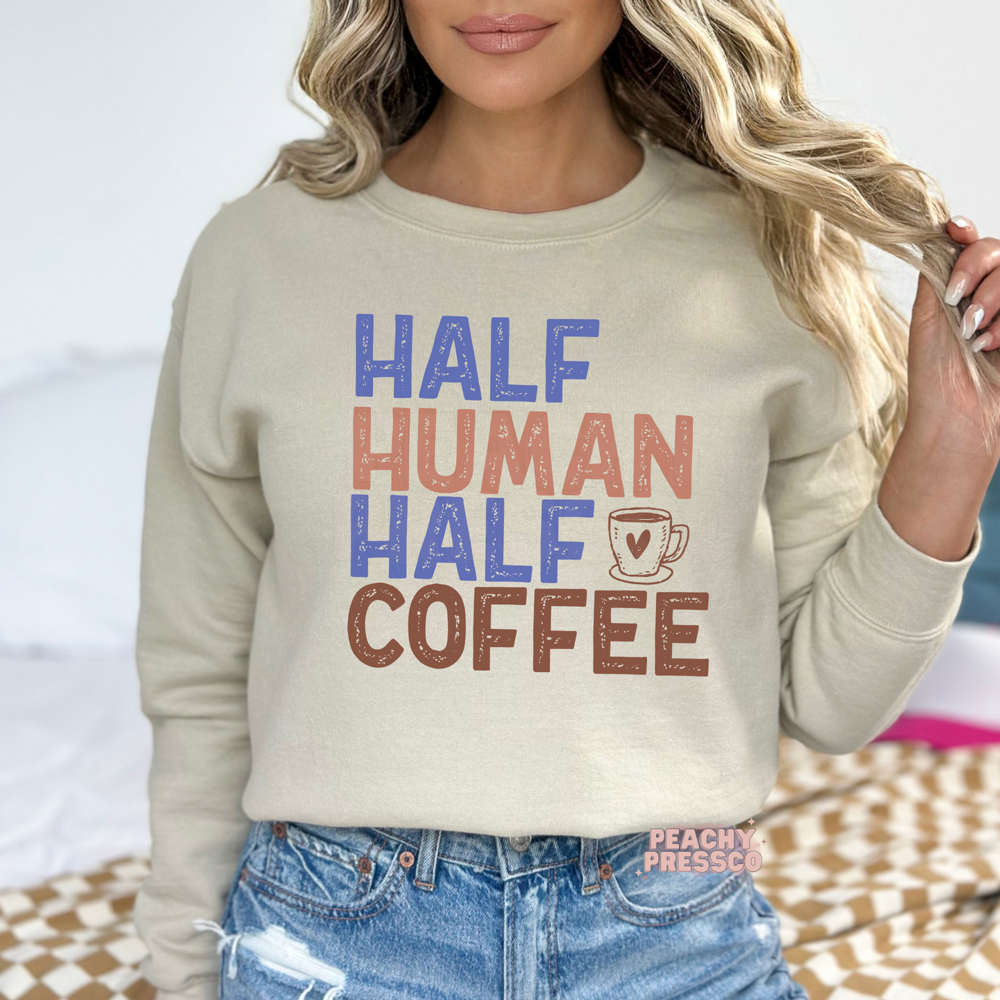 Sand beige graphic sweatshirt featuring the funny "Half Human Half Coffee" coffee lover quote with distressed retro typography.