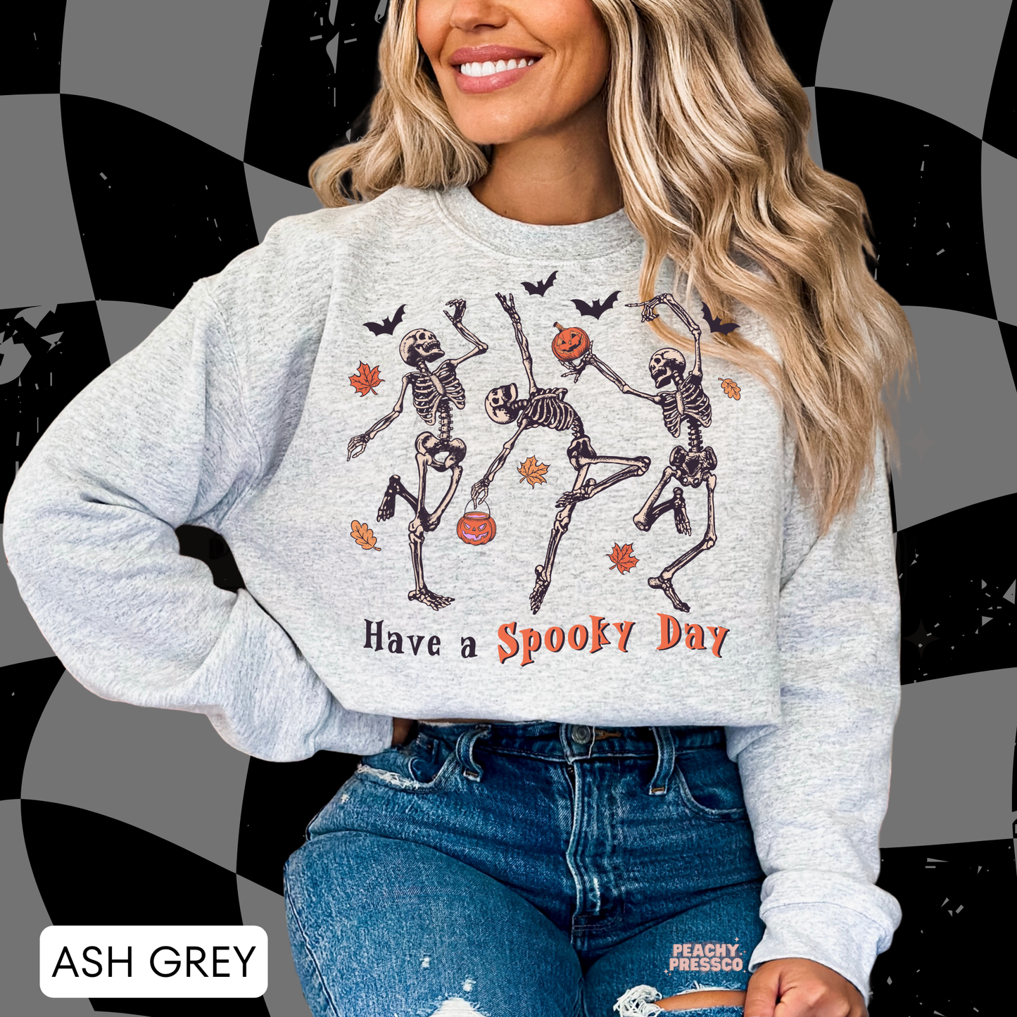 Woman wearing an ash grey crewneck sweatshirt with vintage dancing skeletons, pumpkins and "Have a Spooky Day" Halloween graphic.