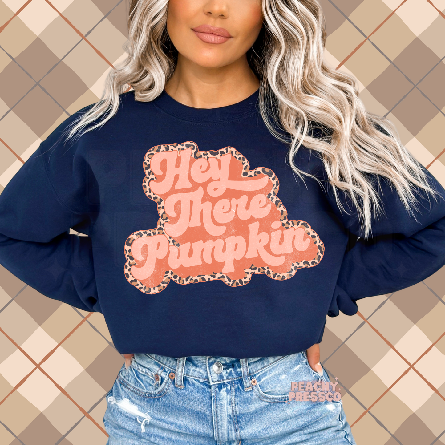 Woman wearing a navy crewneck sweatshirt featuring a retro Hey There Pumpkin graphic with a leopard print outline for autumn.