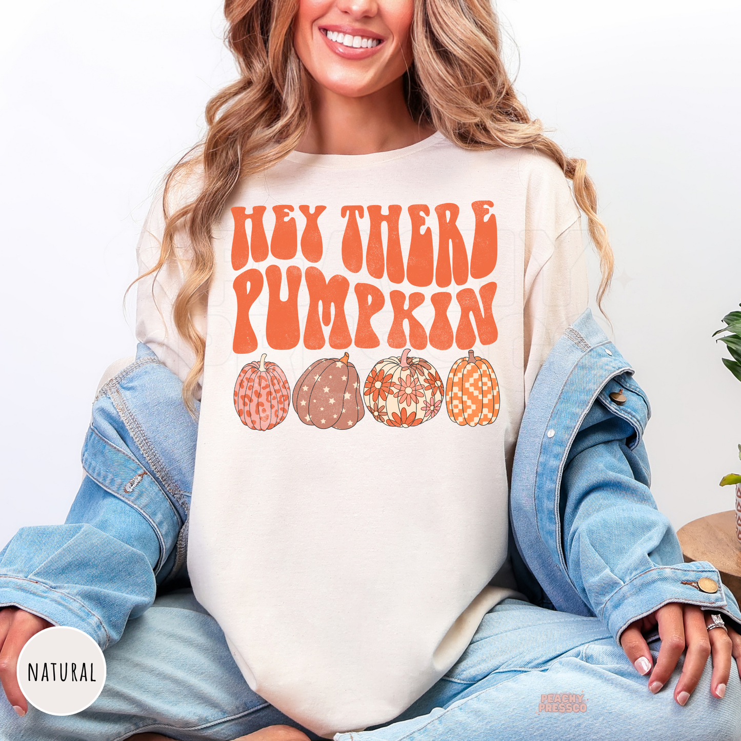 Woman wearing a natural t-shirt with a vintage "Hey There Pumpkin" graphic and four whimsical autumn pumpkins.