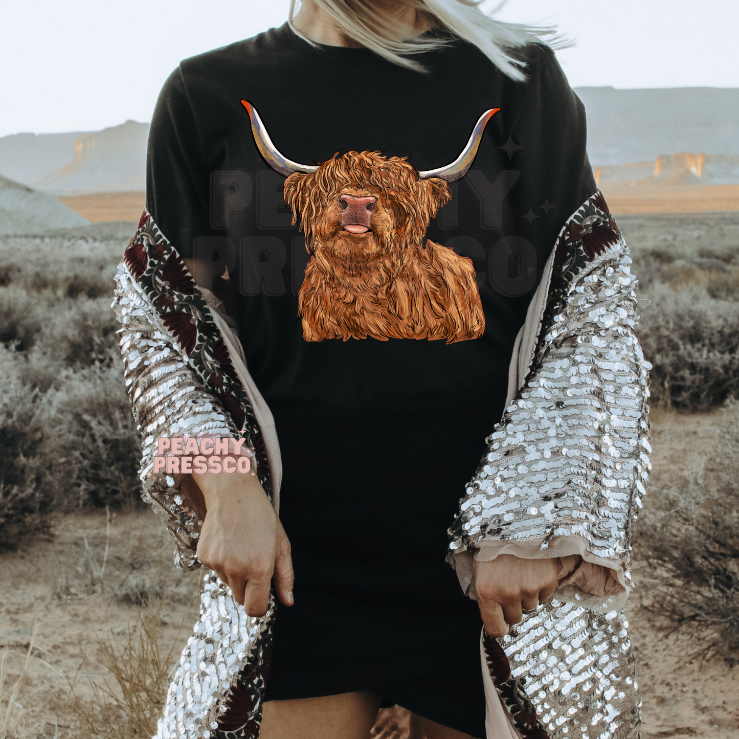 Woman wearing a black t-shirt featuring a realistic Highland cow graphic, perfect for western fashion and farmhouse style.