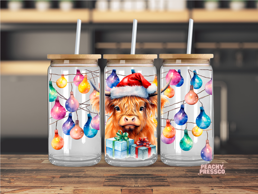16oz glass cup with bamboo lid featuring a watercolor Highland cow wearing a Santa hat surrounded by colorful Christmas lights.