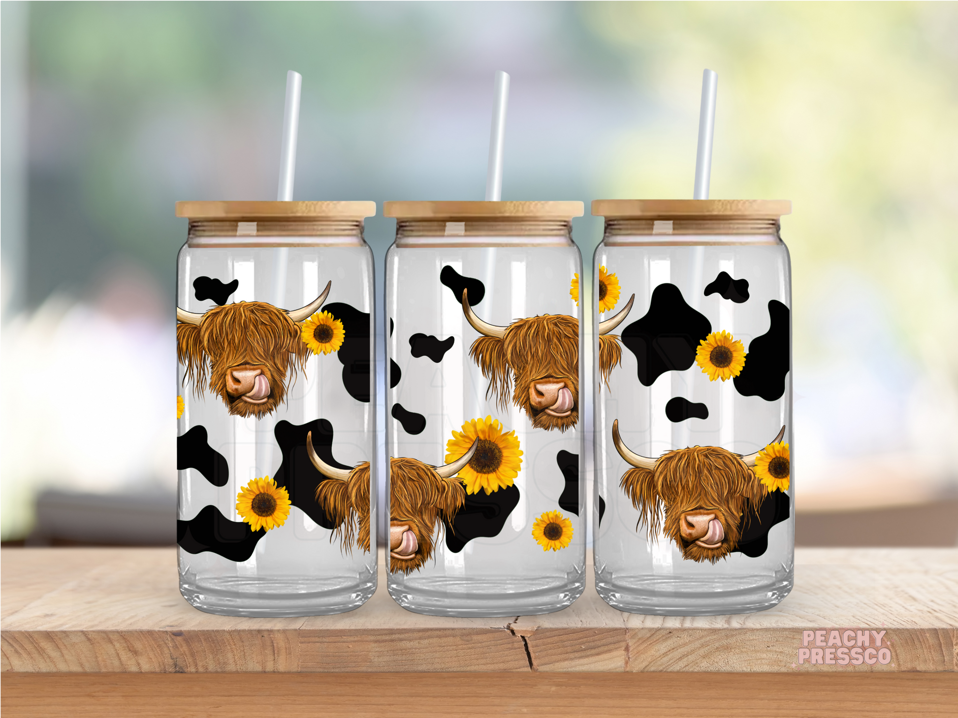 Glass cup featuring repeating Highland cow faces with sunflower accents and black cow print pattern.