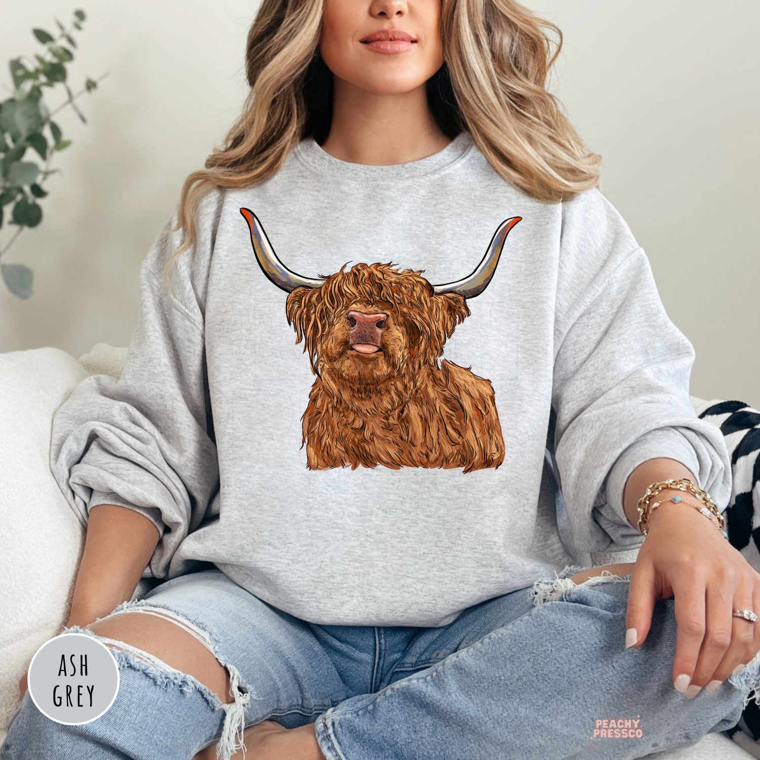 Woman wearing an ash grey sweatshirt featuring a detailed Highland cow graphic with long horns, perfect for western, farmhouse, and country style.