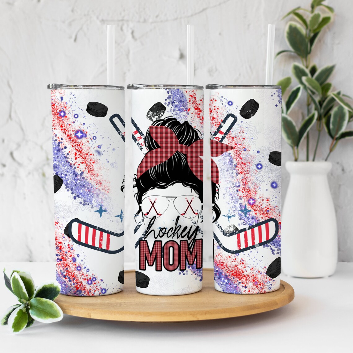 20oz skinny tumbler featuring a messy bun hockey mom design with hockey sticks, pucks, and red, white, and blue glitter accents.