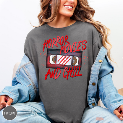 Woman wearing a charcoal crewneck sweatshirt with a Horror Movies and Chill VHS tape graphic layered under a denim jacket for fall.