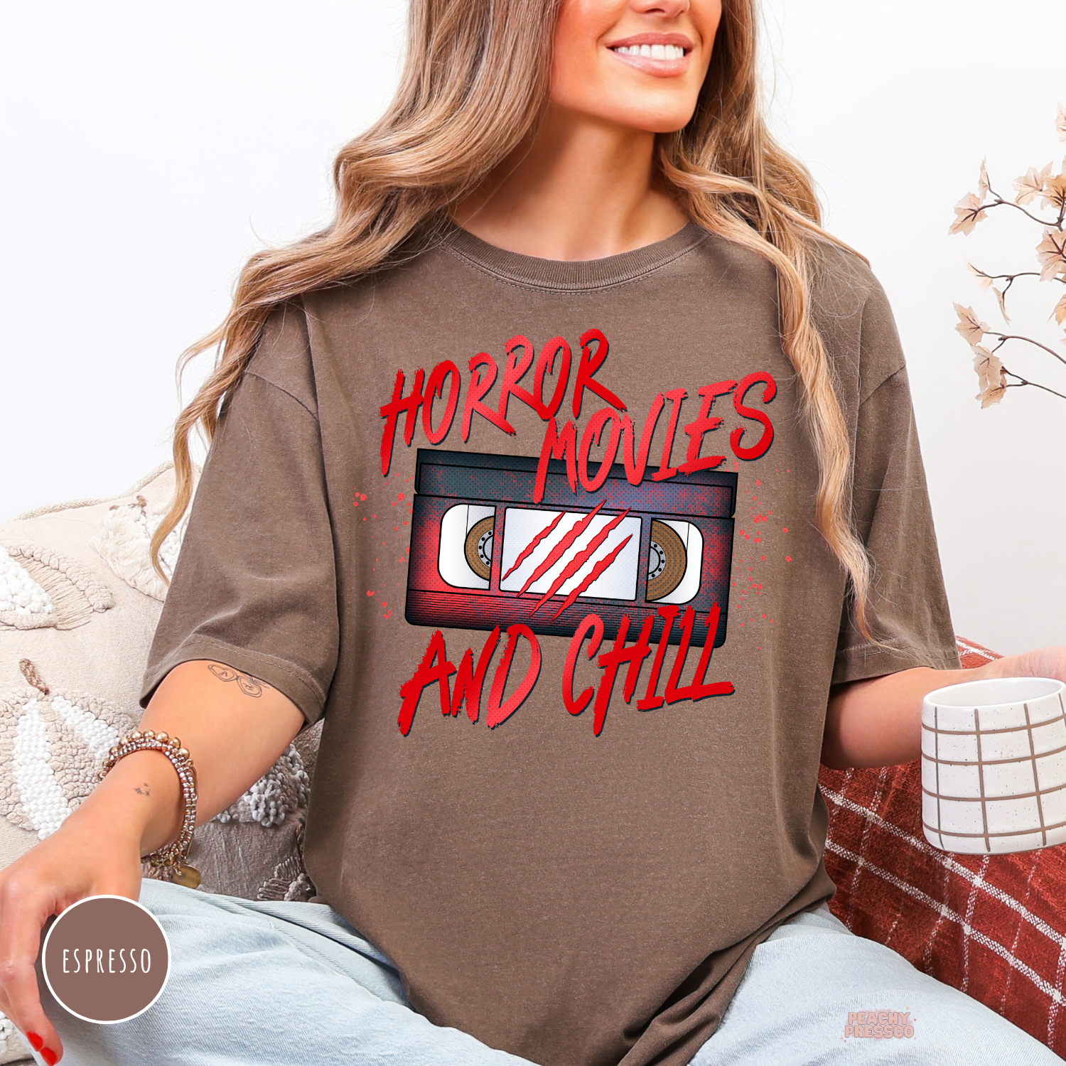 Woman wearing an espresso Comfort Colors t-shirt with a Horror Movies and Chill vintage VHS cassette graphic for spooky season and scary movie nights.