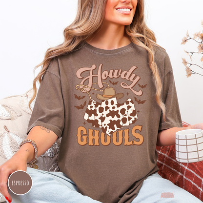 Woman wearing an espresso Comfort Colors t-shirt featuring a Howdy Ghouls western ghost graphic with cow print, cowboy hat, bats and spooky fall design.