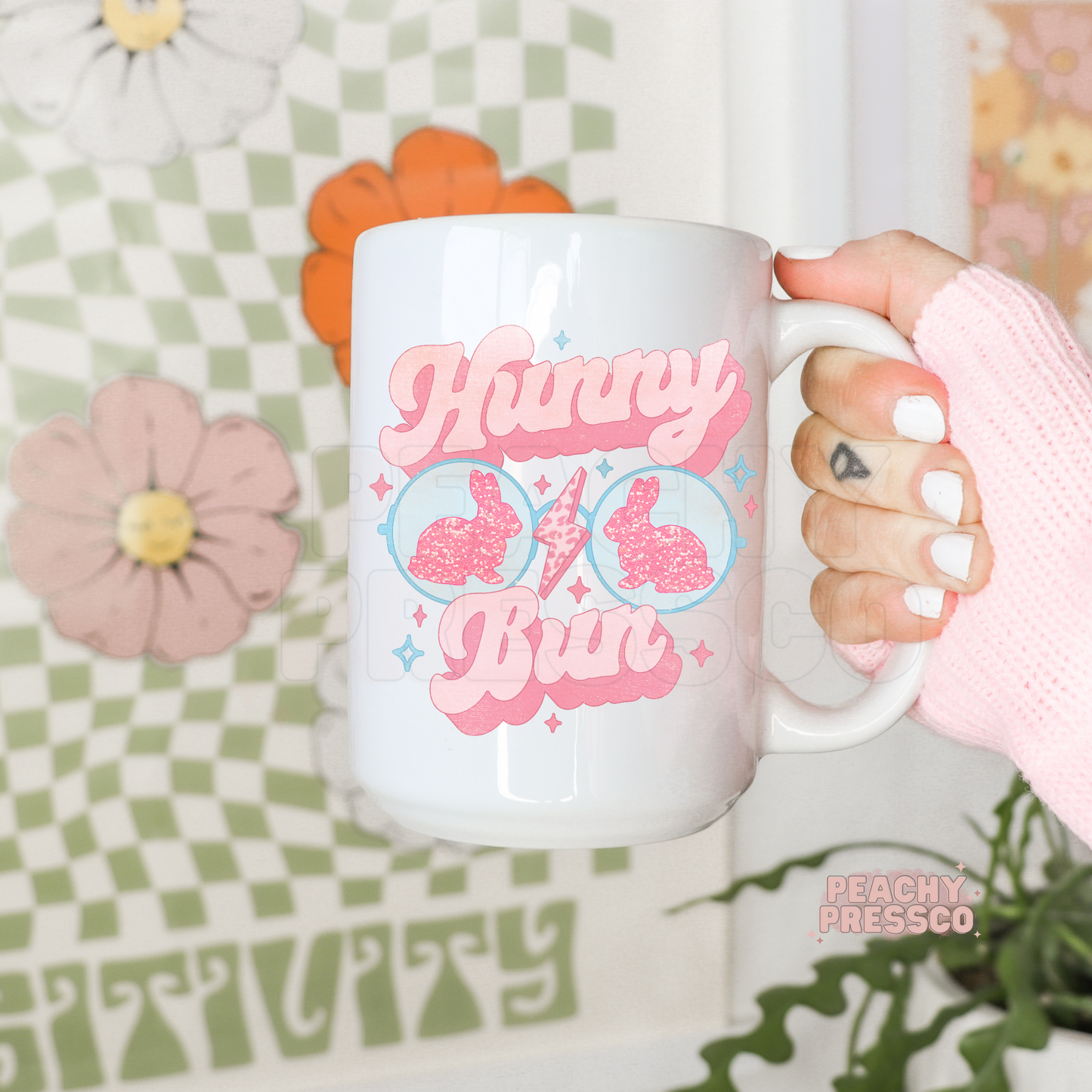 White ceramic Easter coffee mug featuring retro pink "Hunny Bun" lettering with bunny-shaped sunglasses, glitter bunny silhouettes, and cute pastel spring accents.