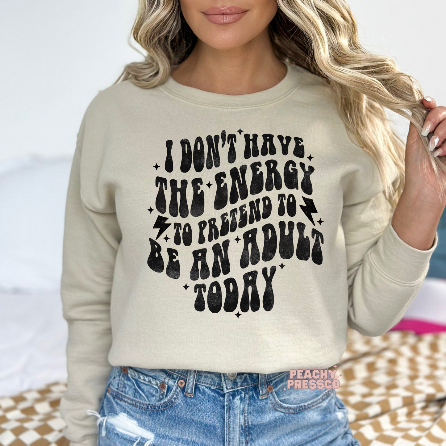 Beige sand crewneck sweatshirt featuring the funny "I Don't Have the Energy to Pretend to Be an Adult Today" graphic in distressed retro lettering.