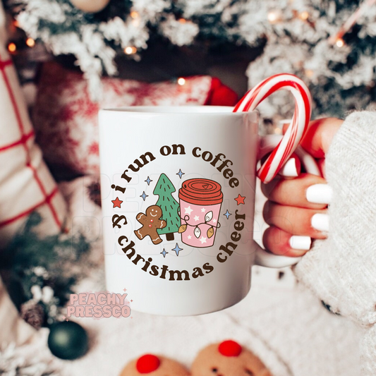 White mug printed with I run on coffee and christmas cheer featuring a cute pink coffee cup, gingerbread man, and Christmas tree.