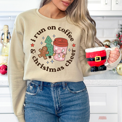 Woman wearing a sand beige coffee and Christmas cheer sweatshirt holding a Santa mug in a festive kitchen background.