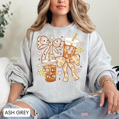 Ash grey iced coffee sweatshirt featuring adorable iced coffee cups, oversized floral bows, pastel hearts, yellow daisies and whimsical star details.