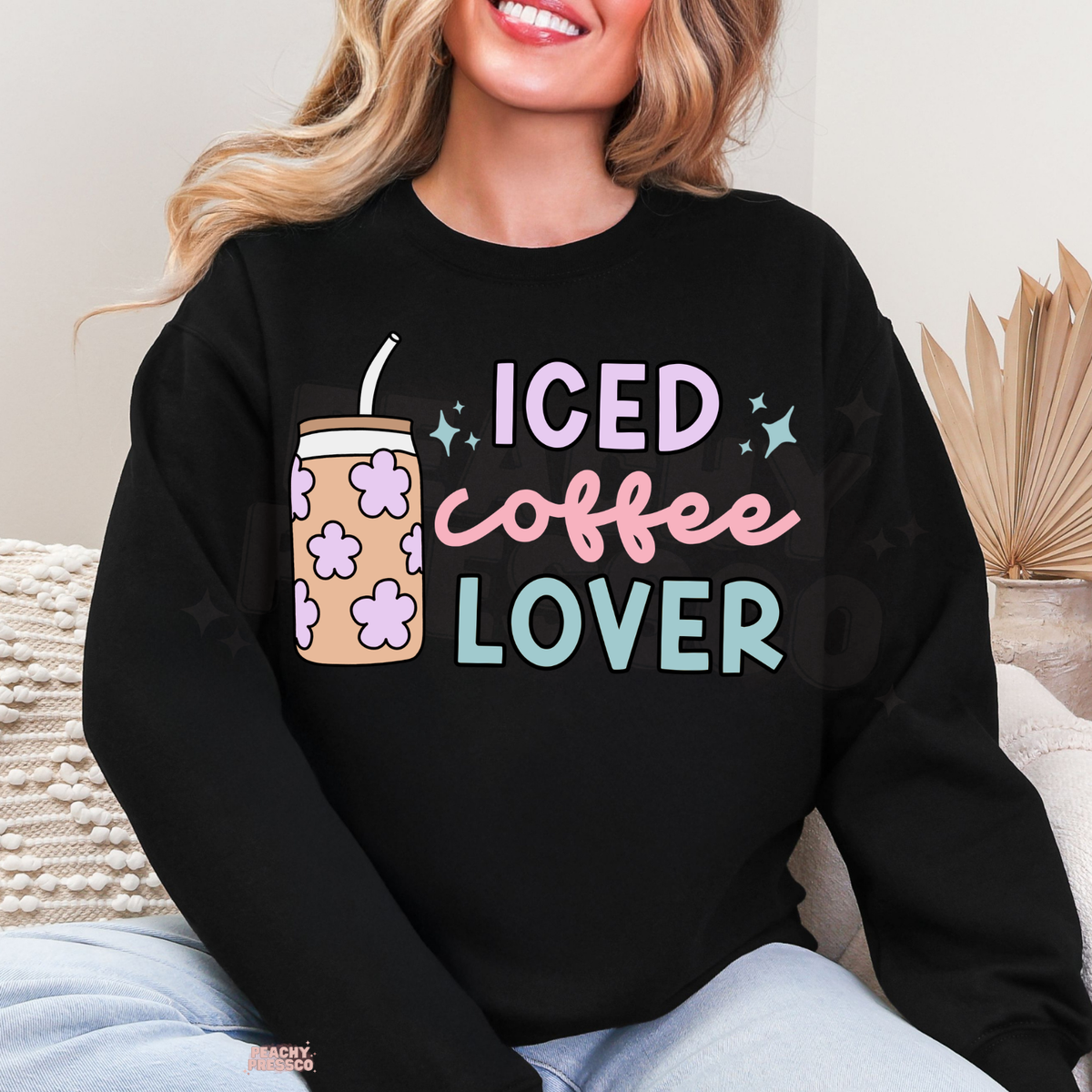 Black Iced Coffee Lover sweatshirt featuring a cute floral iced coffee cup, pastel lavender and pink lettering with teal accents.