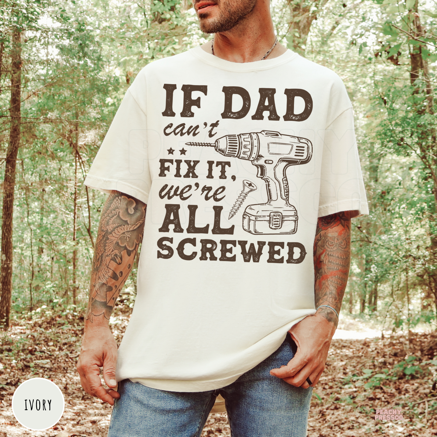 Ivory t-shirt with the funny "If Dad Can't Fix It, We're All Screwed" graphic featuring a cordless drill and screw. Perfect gift for dads who love tools, woodworking, repairs, and DIY projects.