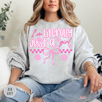 Woman wearing an ash grey crewneck sweatshirt with a pink coquette "I'm Literally Just a Girl" graphic and cute bow illustration.