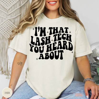 Woman modelling an ivory lash tech T-shirt with the playful I'm That Lash Tech You Heard About design in black lettering.