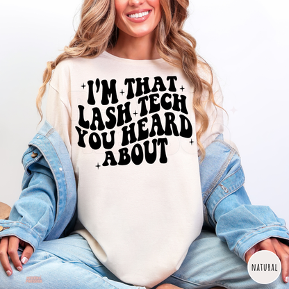 Woman wearing a natural coloured lash technician T-shirt featuring the I'm That Lash Tech You Heard About graphic in bold black lettering.