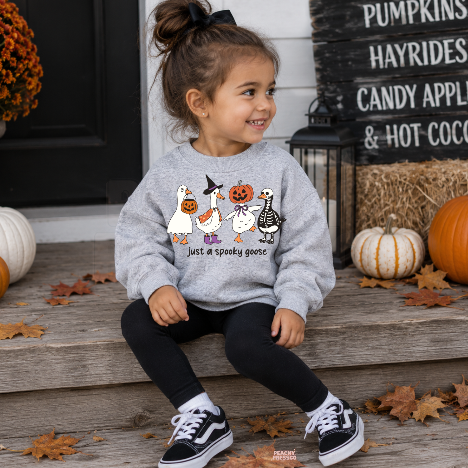 Girl wearing a sport grey Just a Spooky Goose Halloween sweatshirt featuring geese dressed in cute pumpkin, witch and skeleton costumes.