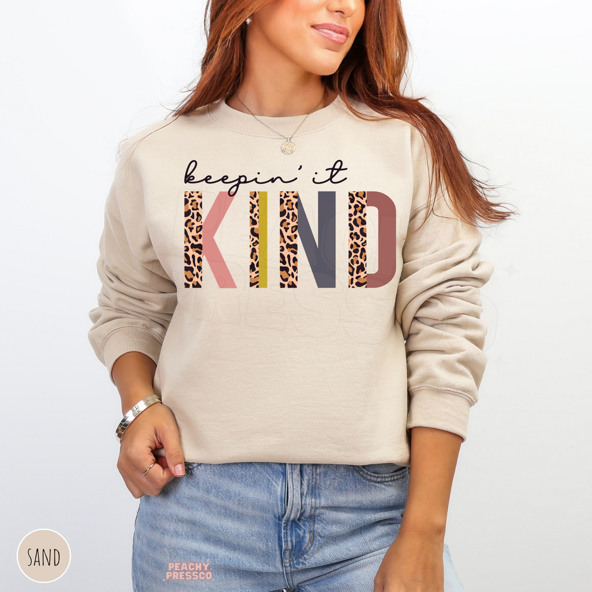 Sand Keepin' It Kind sweatshirt featuring bold leopard print KIND lettering with pink, mustard yellow and earthy retro colors.