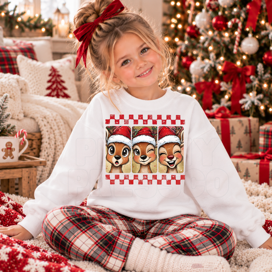 Girl wearing a white kids Christmas sweatshirt featuring three cute reindeer in Santa hats.