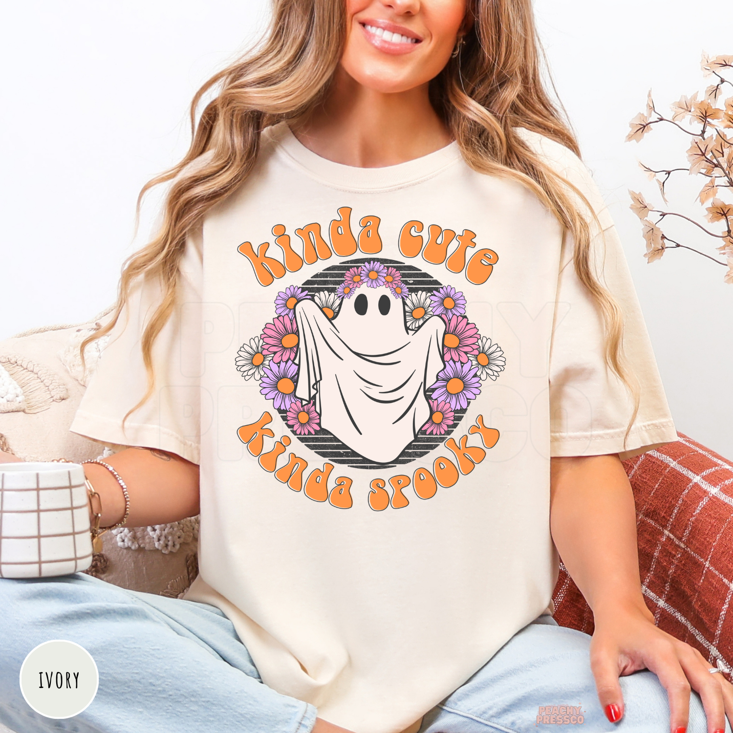 Woman wearing an ivory Kinda Cute Kinda Spooky ghost Halloween graphic t-shirt with a floral ghost design and retro orange lettering.