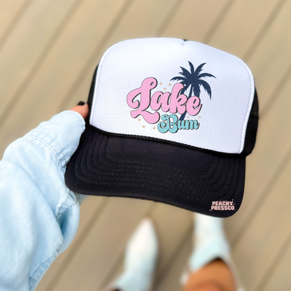 White and black foam trucker hat featuring a bold black "Lake Bum" design. Trendy summer trucker hat perfect for lake days, boating, camping, beach vacations, and everyday casual wear.