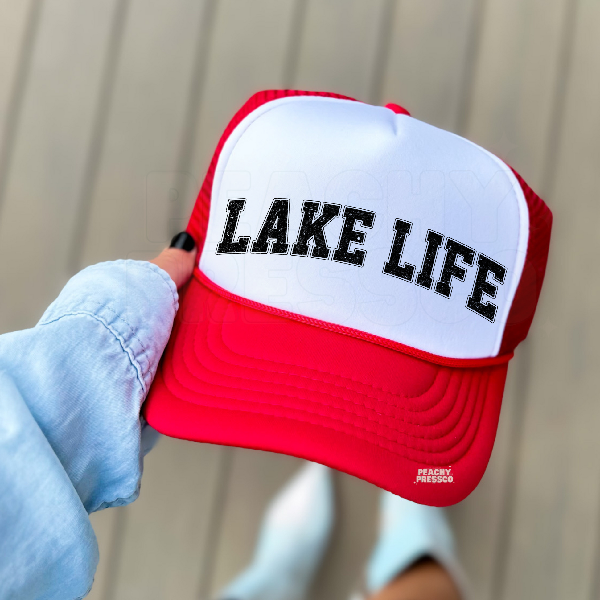 Red and white foam trucker hat featuring distressed "LAKE LIFE" varsity lettering, trendy summer accessory for boating, fishing, lake vacations, and cabin getaways.