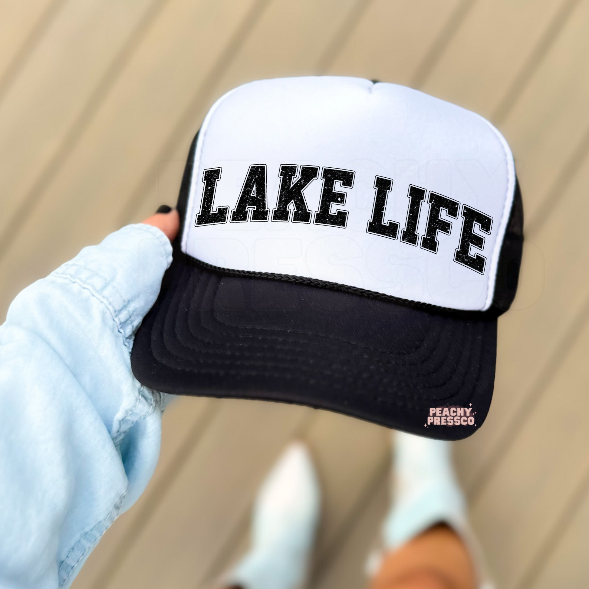 White and black foam trucker hat with distressed "LAKE LIFE" collegiate lettering, stylish summer hat for boating, lake trips, cabin weekends, and beach vacations.