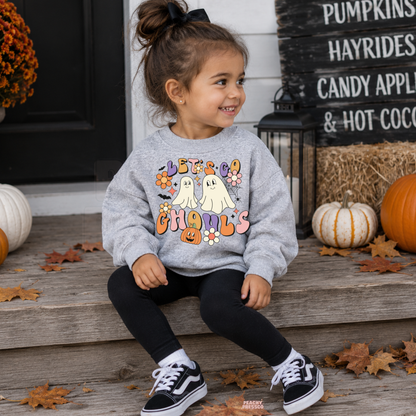 Girl wearing a sport grey Let’s Go Ghouls Halloween sweatshirt with retro ghosts, colorful flowers and a pumpkin graphic.