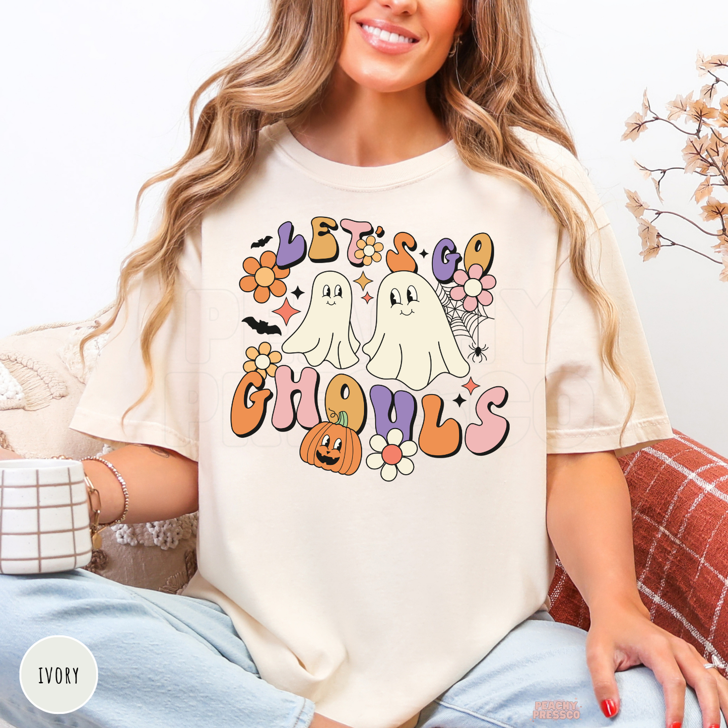 Ivory Let’s Go Ghouls Halloween shirt featuring cute ghosts, pumpkin, bats, spiderweb and retro floral design