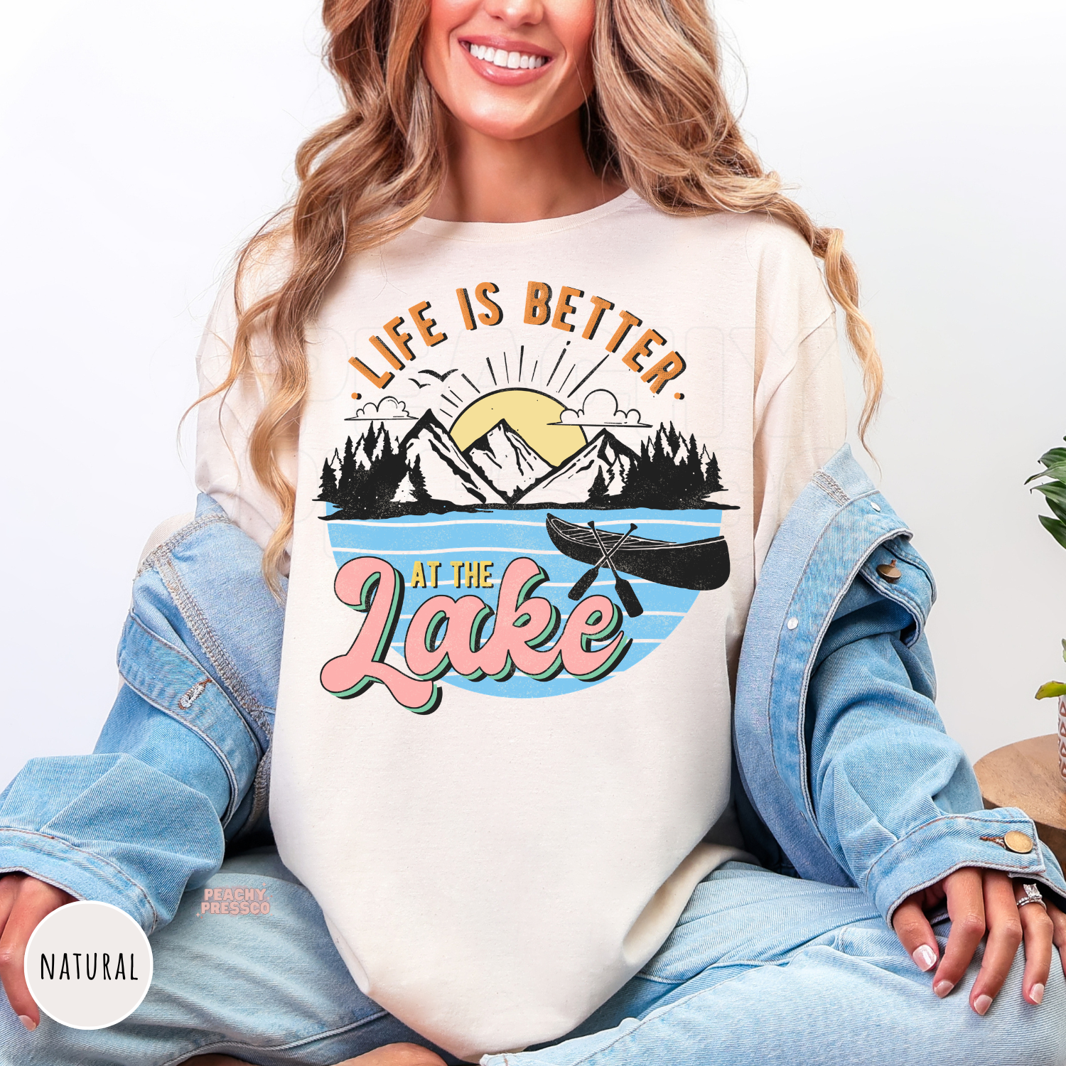 Natural Comfort Colors t-shirt with a vintage-inspired lake design featuring mountains, canoe, pine trees, blue water, sunshine, and "Life Is Better at the Lake."