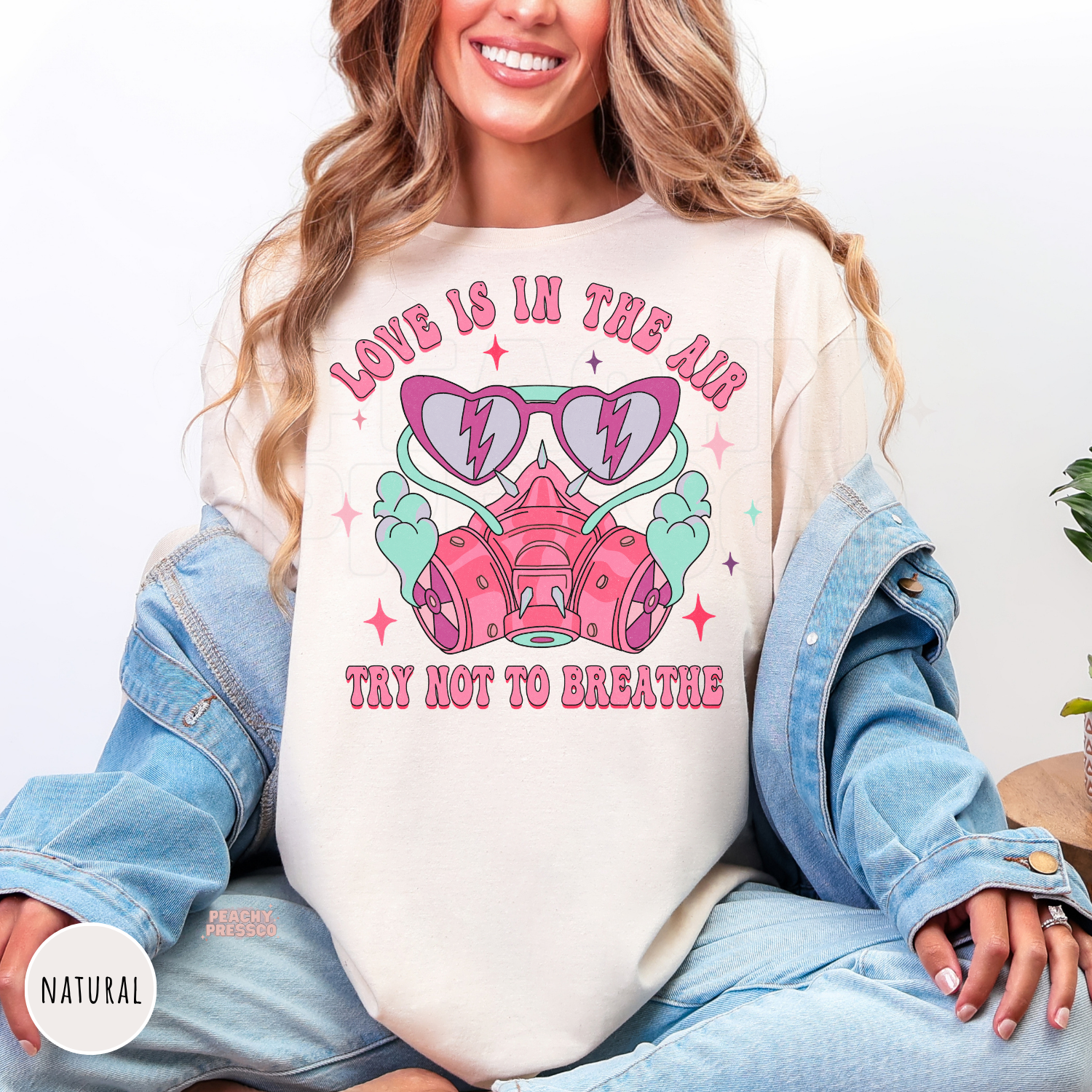 Love Is In The Air Try Not To Breathe graphic printed on a natural unisex shirt featuring a retro pink respirator mask, heart sunglasses, and Valentine's Day design.