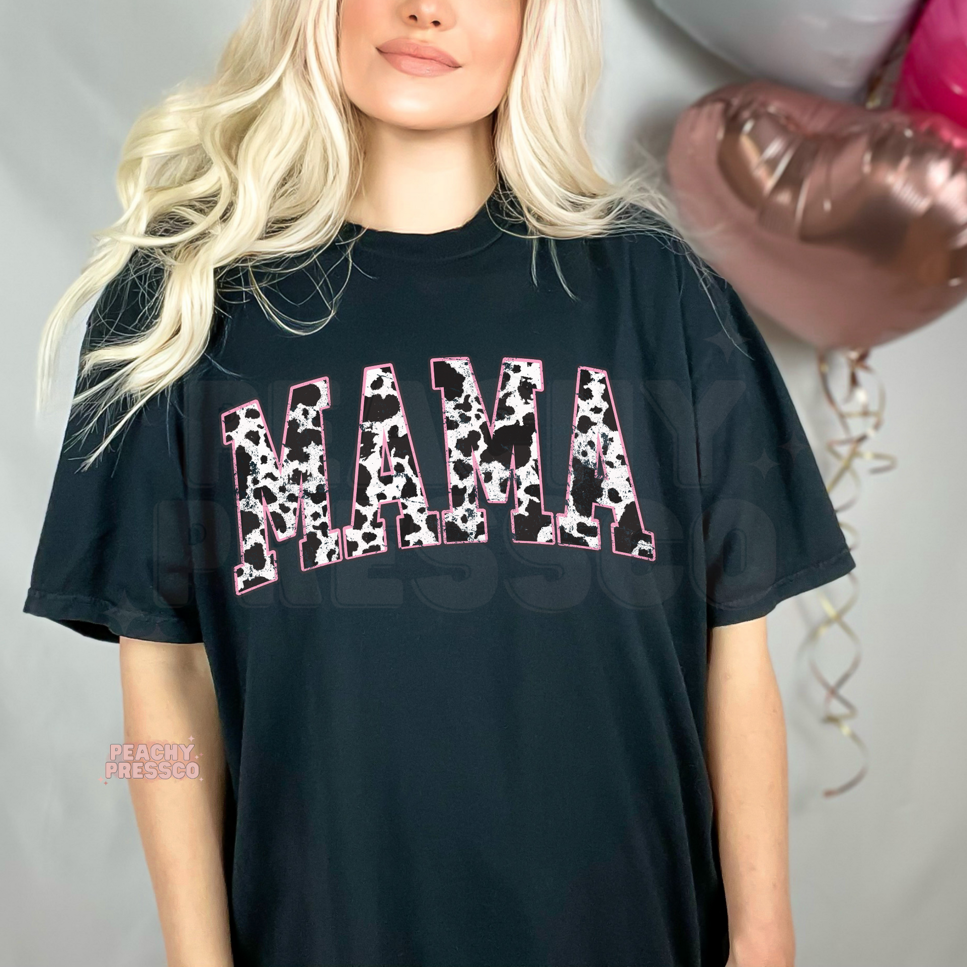 Black t-shirt featuring a distressed cow print "MAMA" graphic with pink accents. Trendy western mama tee for casual everyday outfits and Mother's Day gifts.