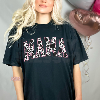 Black t-shirt featuring a distressed cow print "MAMA" graphic with pink accents. Trendy western mama tee for casual everyday outfits and Mother's Day gifts.