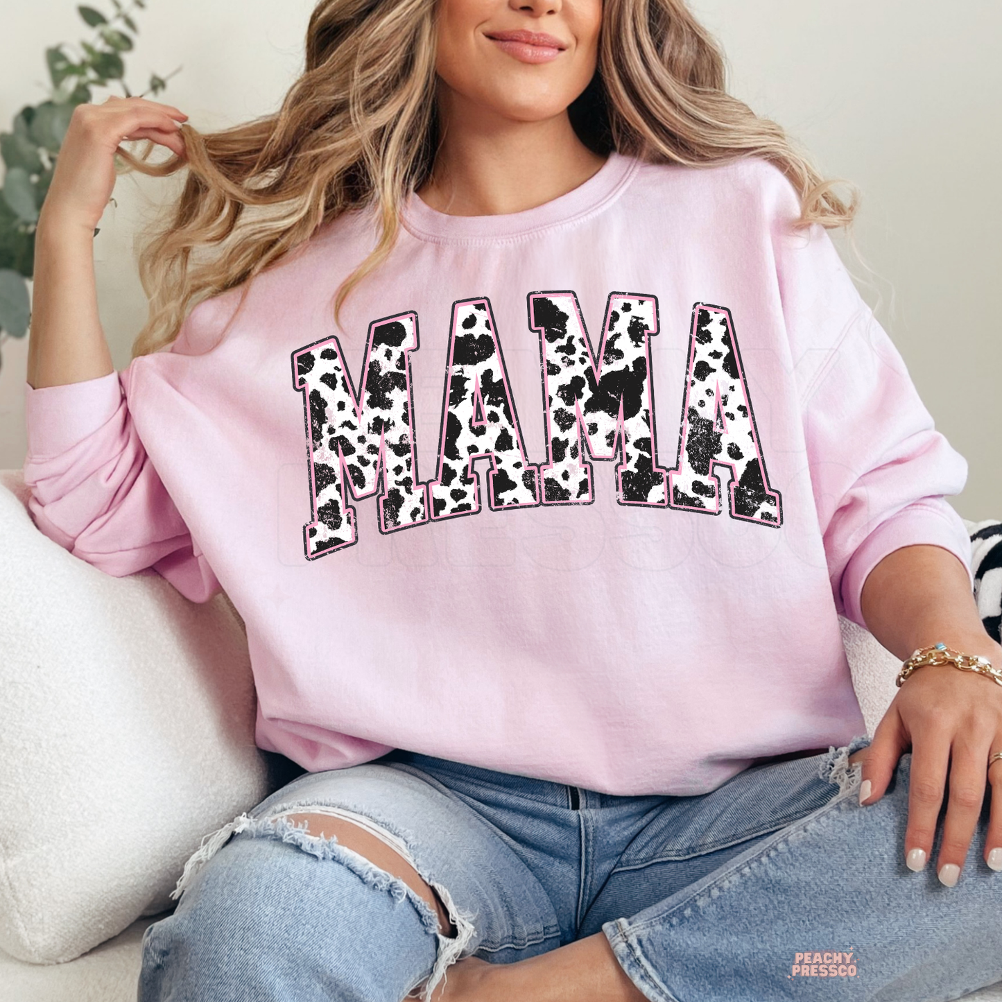 Light pink sweatshirt featuring a distressed cow print "MAMA" graphic with a pink outline. Cute western-inspired mama sweatshirt and thoughtful Mother's Day gift.