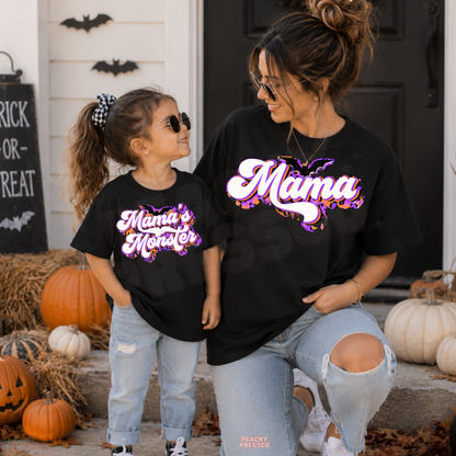 Mama and daughter wearing matching black Mama and Mama’s Monster Halloween T-shirts with retro purple and orange graphics.