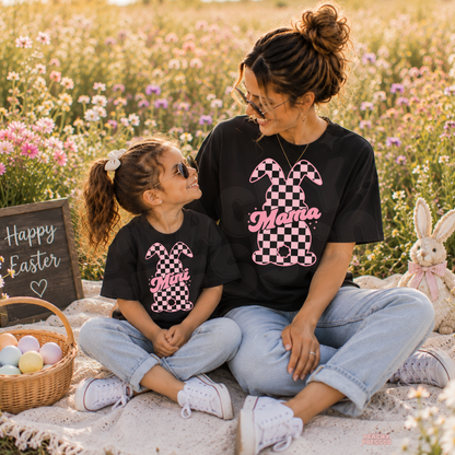 Mom and daughter wearing matching black checkered bunny Mama and Mini Easter t-shirts in a flower field with Easter basket and bunny decor.