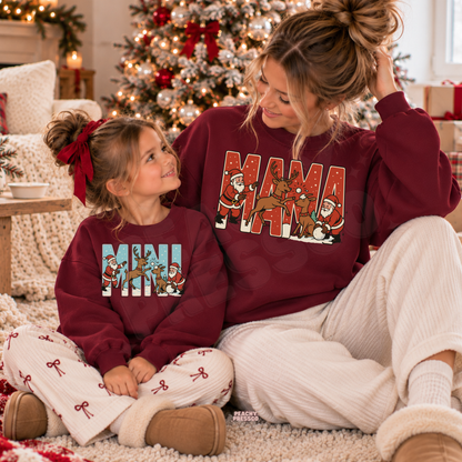 Mom and daughter wearing matching maroon Mama and Mini Christmas crewneck sweatshirts with Santa and reindeer graphic.