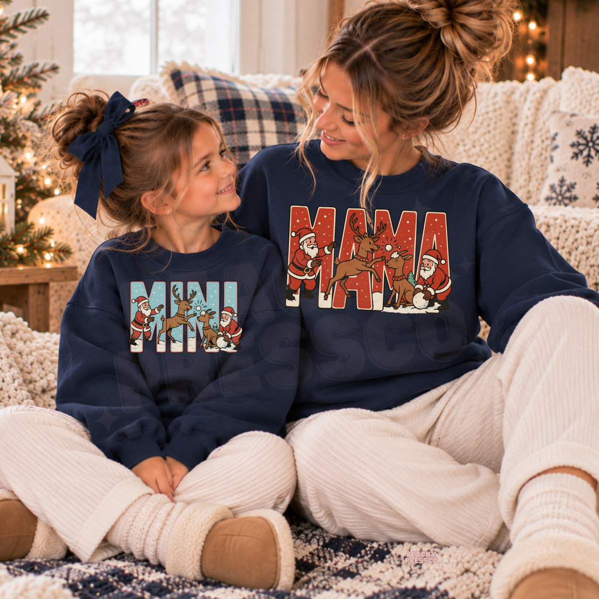 Mom and daughter wearing matching navy Mama and Mini Christmas sweatshirts with retro Santa and reindeer design.