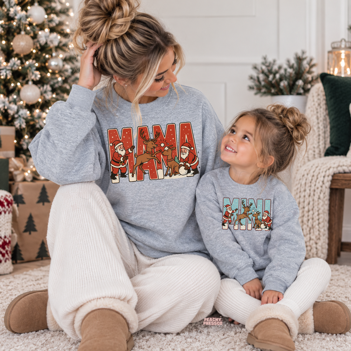 Mom and daughter wearing matching sport grey Mama and Mini Christmas sweatshirts with retro Santa and reindeer graphic.
