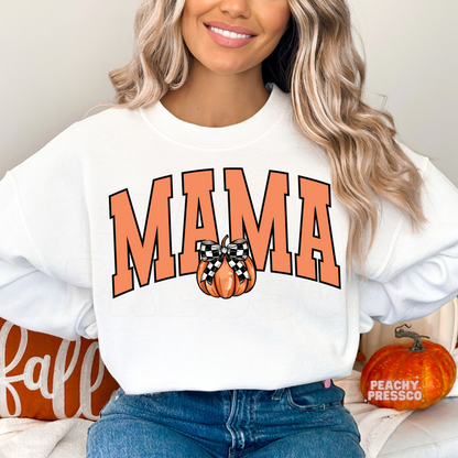 Woman wearing a white crewneck sweatshirt featuring a Mama graphic with a cute pumpkin and buffalo plaid bow.