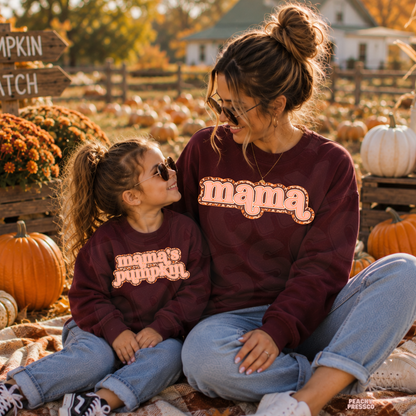 Mom and daughter wearing matching maroon "Mama" and "Mama's Pumpkin" sweatshirts while enjoying a pumpkin patch in autumn.