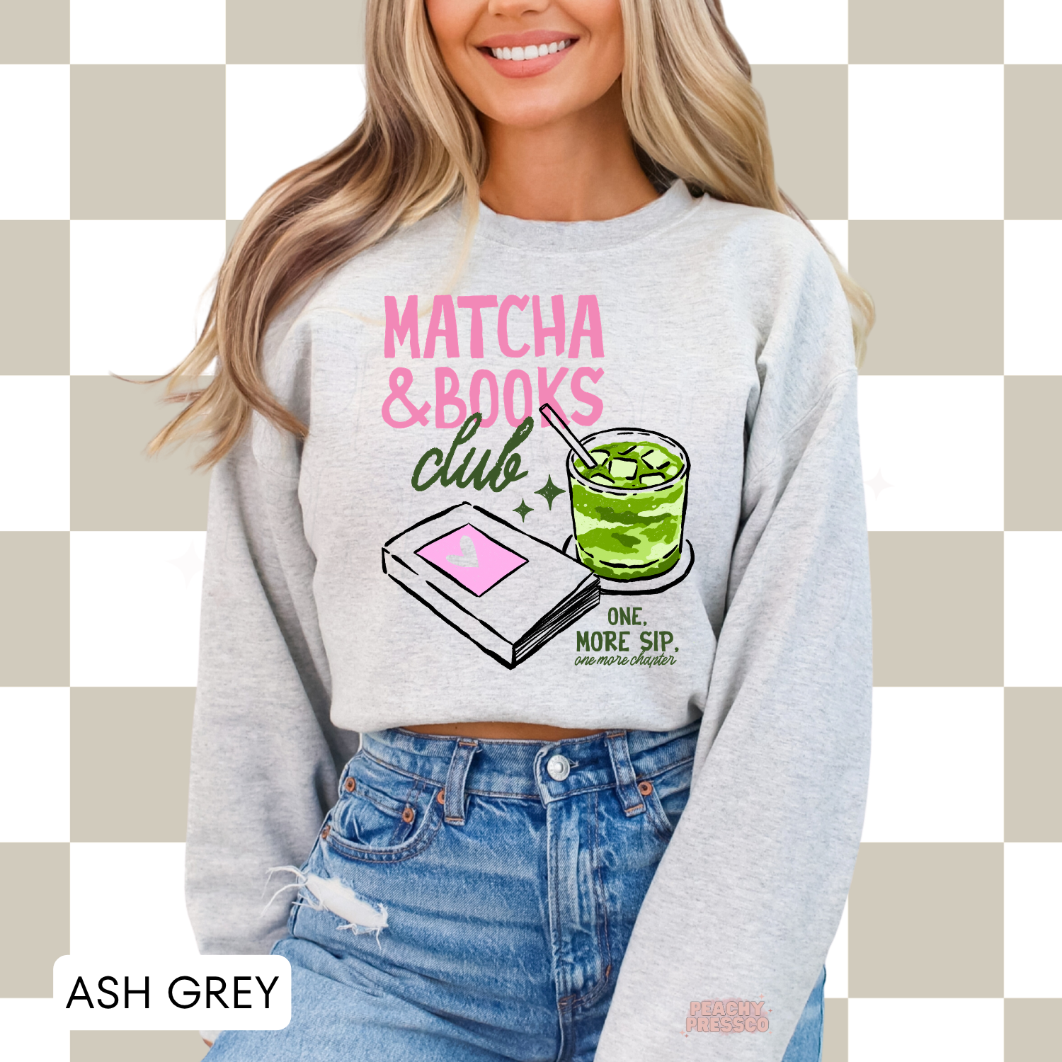 Woman wearing an ash grey crewneck sweatshirt featuring the Matcha & Books Club graphic with an iced matcha latte, book illustration, and the phrase "One More Sip, One More Chapter." Cozy oversized sweatshirt for book lovers.