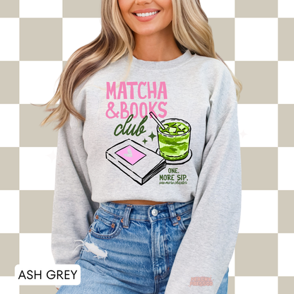 Woman wearing an ash grey crewneck sweatshirt featuring the Matcha & Books Club graphic with an iced matcha latte, book illustration, and the phrase "One More Sip, One More Chapter." Cozy oversized sweatshirt for book lovers.