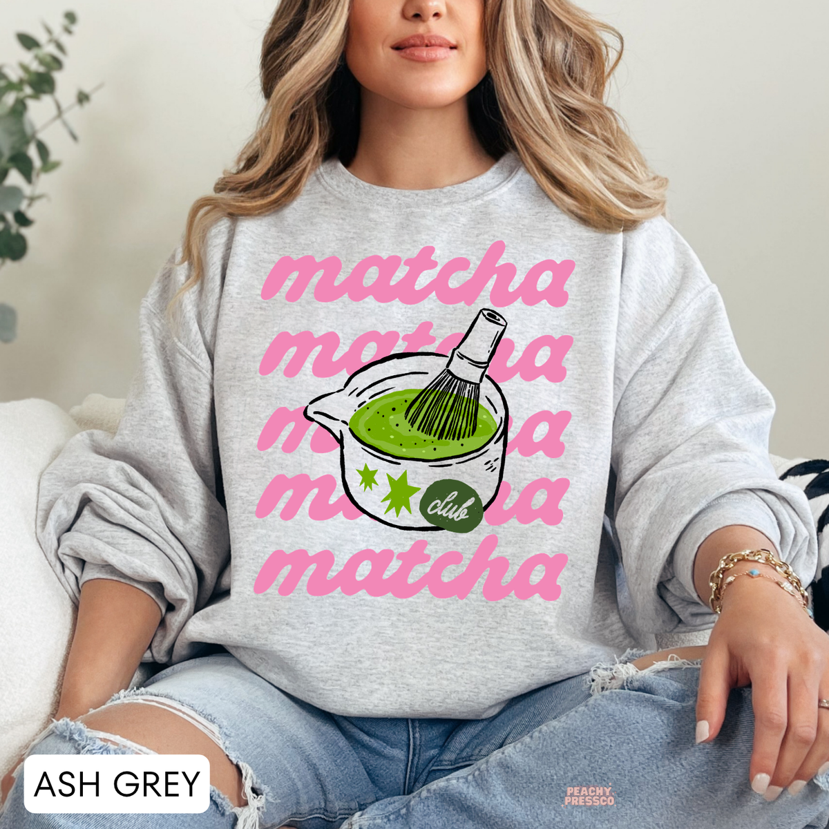 Ash grey Matcha Club sweatshirt with repeated pink matcha lettering, green matcha tea bowl, bamboo whisk illustration, and playful green stars.