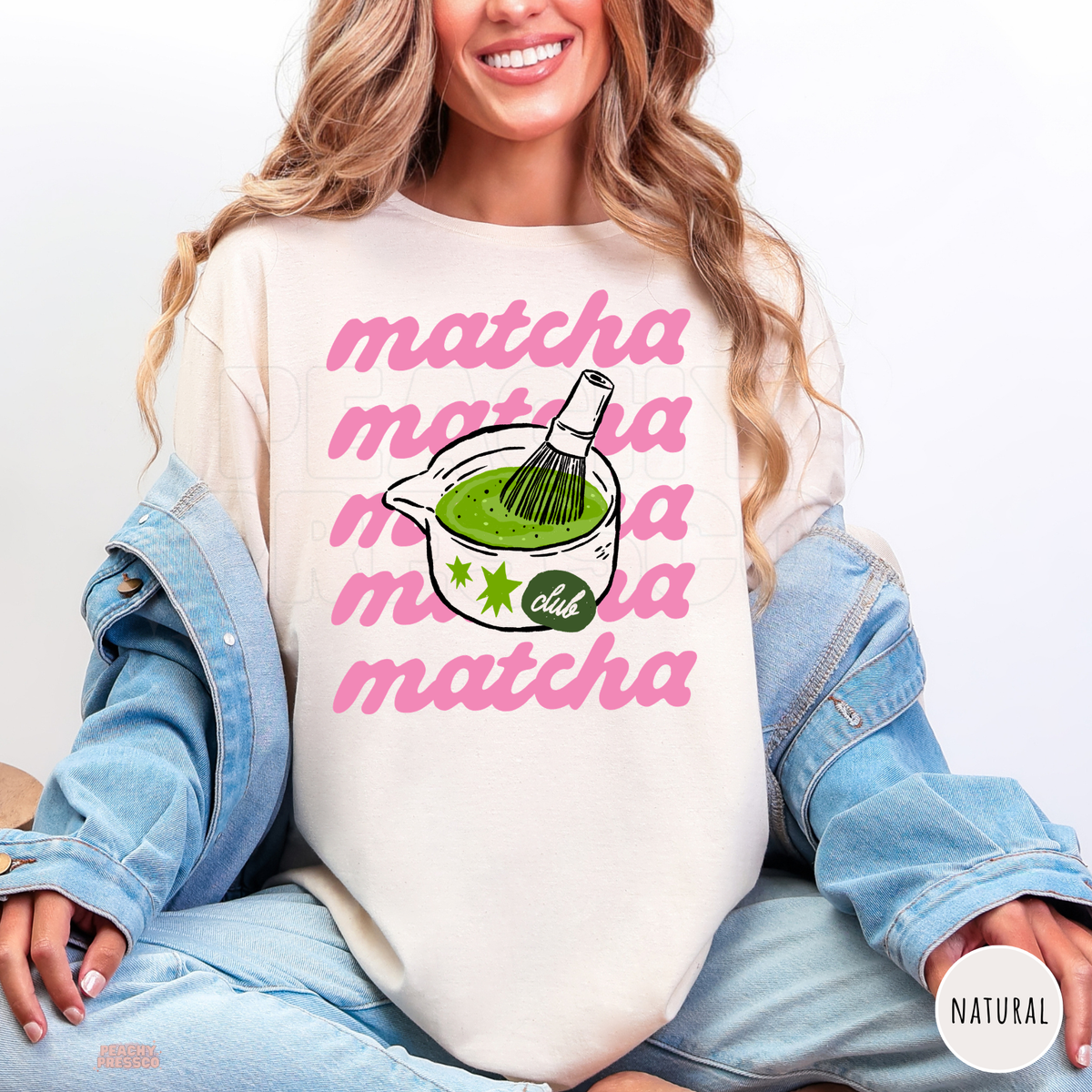 Natural Matcha Club shirt with bold pink repeated matcha text, illustrated green matcha tea bowl, bamboo whisk, and green star accents.